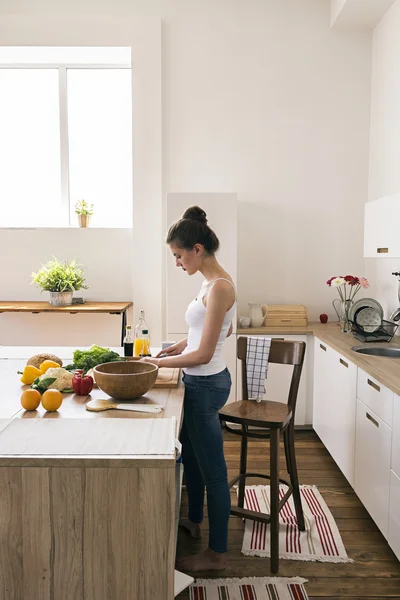 Jovem mulher preparando salada na cozinha — Fotografia de Stock