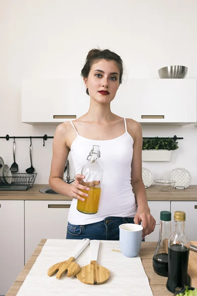 Retrato de morena con botella de zumo de naranja en la cocina —  Fotos de Stock