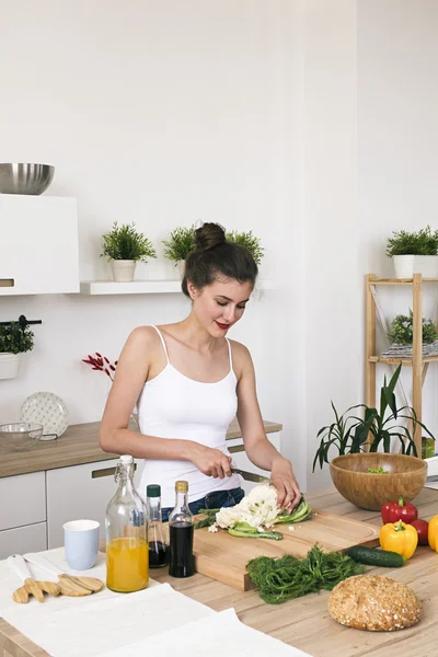 Porträt einer lächelnden Hausfrau, die Blumenkohl in der Küche schneidet — Stockfoto