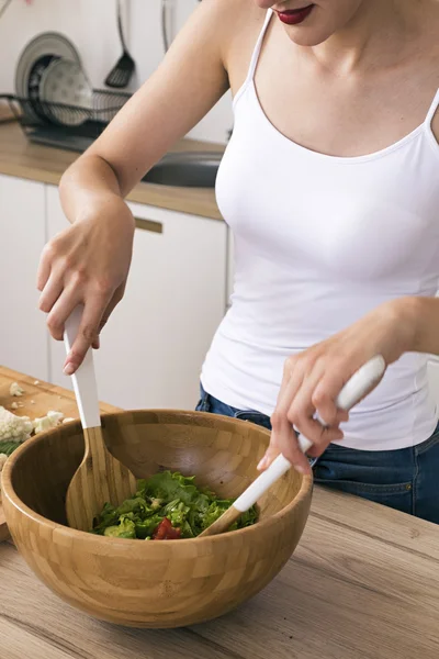Домохозяйка смешивает салат в деревянной чаше — стоковое фото