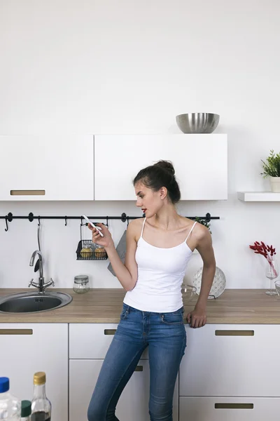 Mujer en la cocina usando teléfono celular —  Fotos de Stock