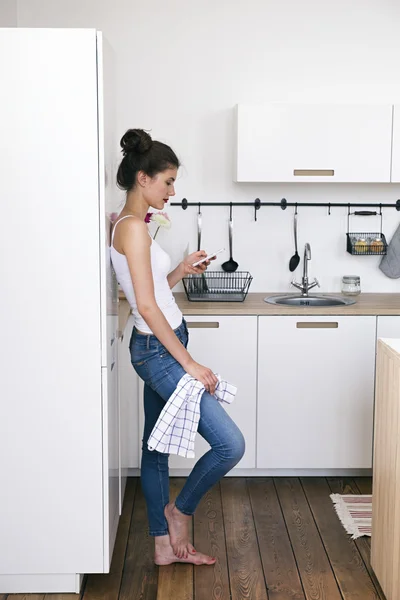 Menina descalça usando telefone celular na cozinha — Fotografia de Stock