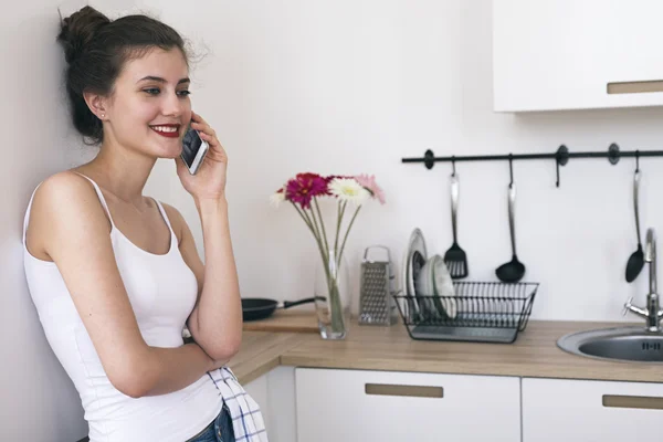 Uśmiechnięta brunetka rozmowy przez telefon w kuchni — Zdjęcie stockowe