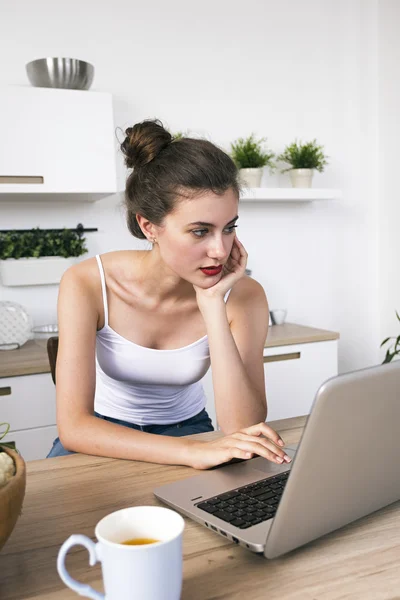 Porträtt av vacker brunett med laptop i köket — Stockfoto