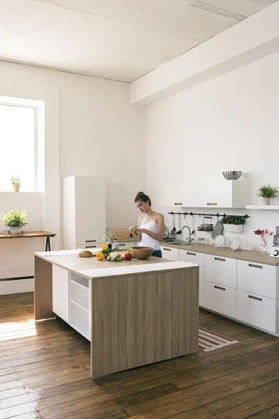 Mujer morena preparando ensalada de verduras en la cocina Fotos de stock libres de derechos