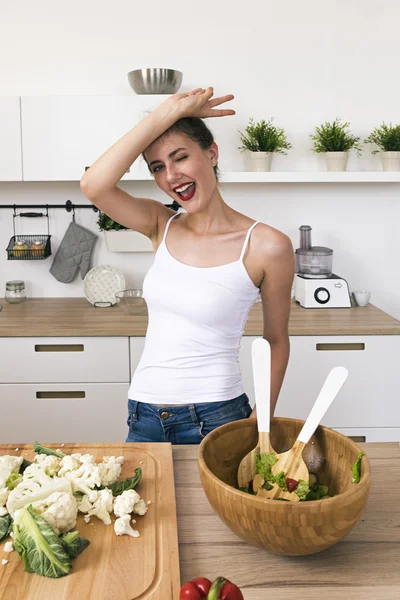 Vrolijke brunette tonen vredesteken en winking camera in keuken Stockafbeelding