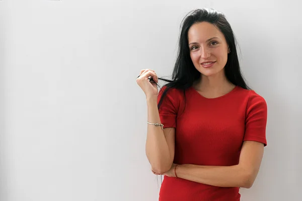 Femme souriante en robe rouge s'embrassant et tenant les cheveux d'une main — Photo