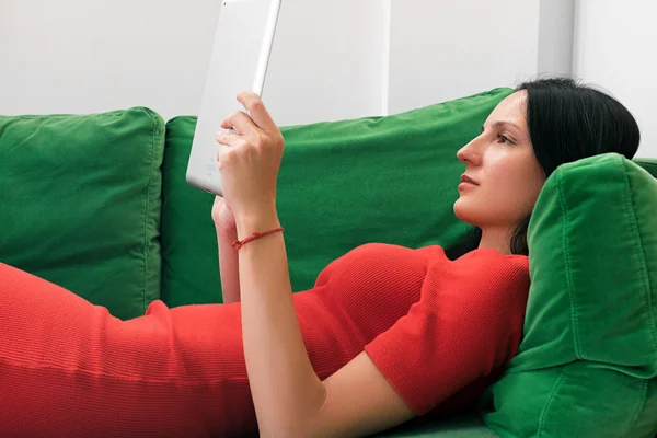 Femme utilisant une tablette sur canapé vert — Photo