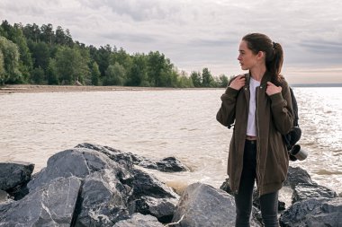 Genç esmer backpacker uzakta kayalık kıyıda seyir