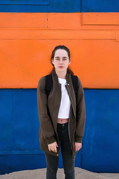 Jovem viajante feminino com mochila contra de parede brilhante — Fotografia de Stock