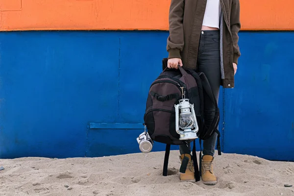 Неузнаваемый путешественник с рюкзаком на песке против красочного здания — стоковое фото