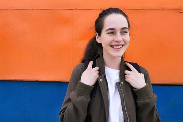 Menina viajante feliz com mochila contra de parede colorida — Fotografia de Stock