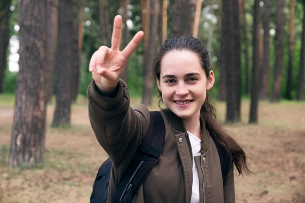 Feliz chica adolescente mochilero mostrando signo de paz en la cámara — Foto de Stock