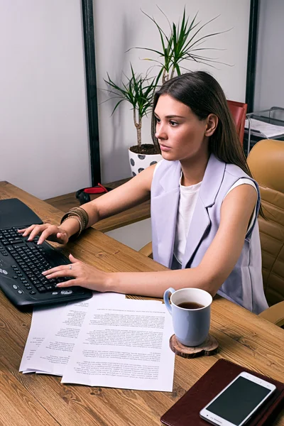 Seriöse Geschäftsfrau arbeitet am Computer mit Tasse Kaffee auf dem Tisch — Stockfoto