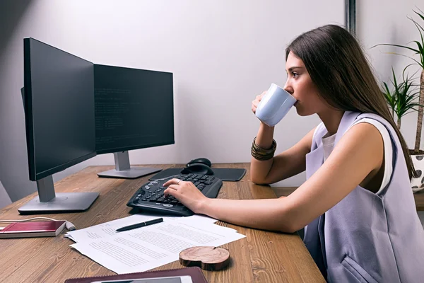 Seitenansicht einer brünetten Geschäftsfrau, die im Büro am Computer arbeitet — Stockfoto