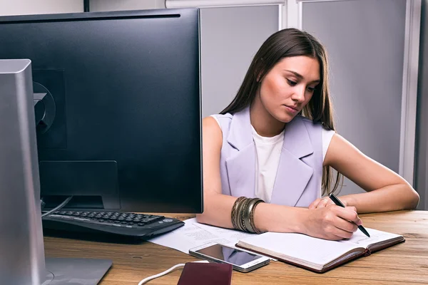 Lugn och allvarlig brunett skriver i anteckningsboken — Stockfoto