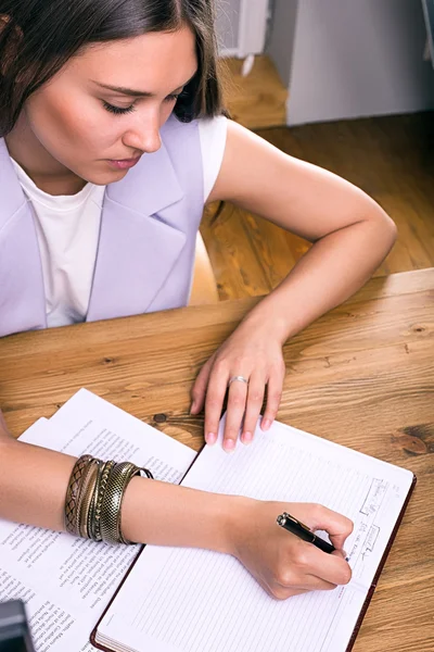 Businesswoman writing agenda in office — Stock Photo, Image
