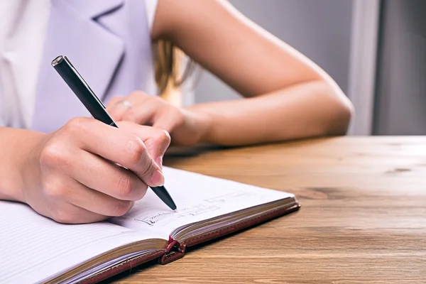 Zbliżenie dłoni kobiece pisanie w notesie — Zdjęcie stockowe