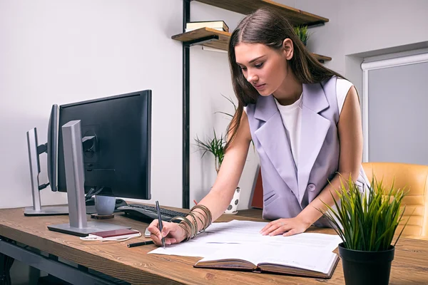 Brünette Frau macht sich Notizen über Dokumente — Stockfoto