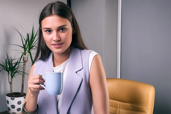 Элегантная деловая женщина с напитком в офисе — стоковое фото