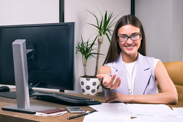 Lächelnde Geschäftsfrau am Tisch mit vor die Kamera gezückter Hand — Stockfoto