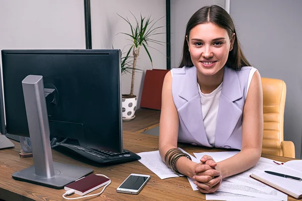 Glad ung affärskvinna vid skrivbord tittar på kameran — Stockfoto