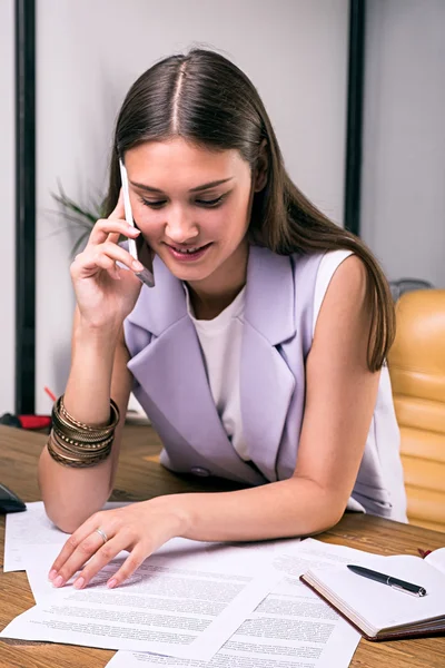 Sonriente morena empresaria usando teléfono móvil en el lugar de trabajo — Foto de Stock