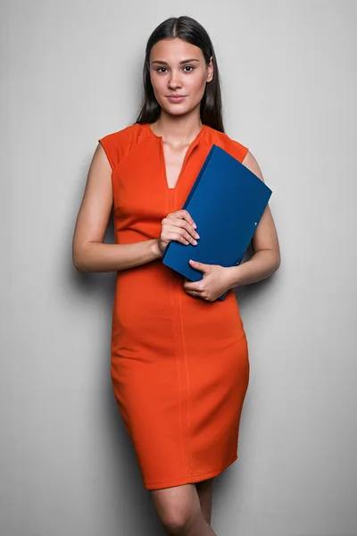 Morena elegante em vestido vermelho com pasta azul — Fotografia de Stock