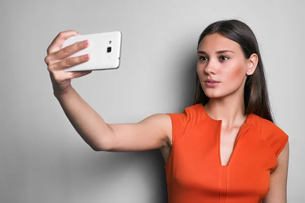 Beautiful woman in red taking selfie using cell — Stock Photo, Image