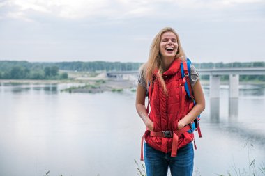 Sırt çantası ile sarışın kız nehirde gülüyor