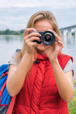Sarışın backpacker dijital kamera kullanarak kırmızı yelek