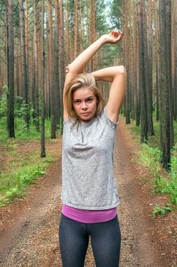 Genç kadın atlet orman kollarında germe