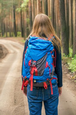 Orman yolu üzerinde sırt çantası ile tanınmaz halde kadın