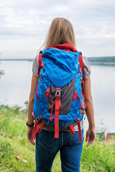 Невпізнавана жінка-мандрівник з рюкзаком на березі річки — стокове фото