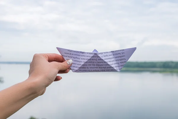 Mano tenendo barca di carta sullo sfondo del fiume — Foto Stock