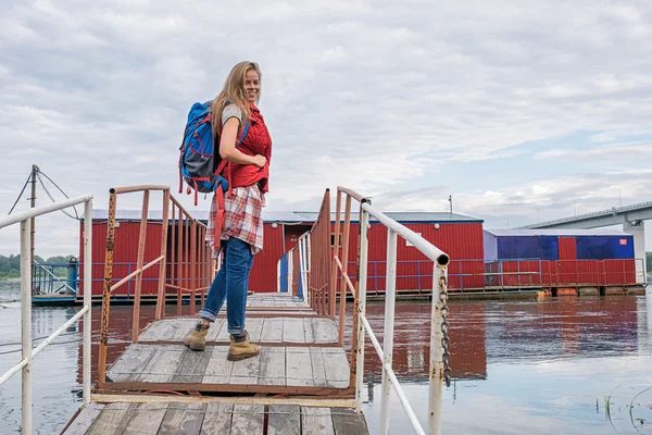 Mooi en lachende backpacker op rivier brug — Stockfoto