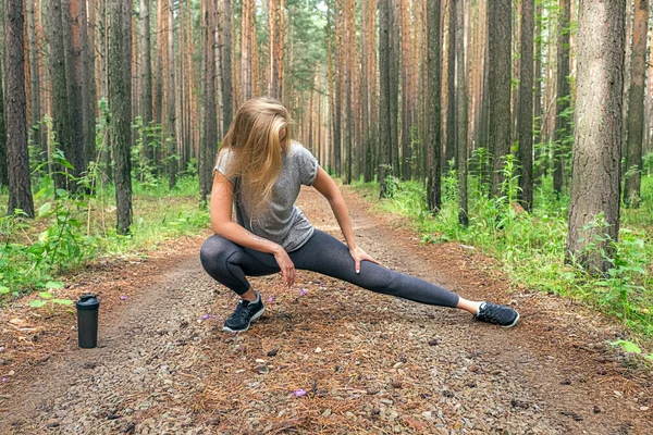 Flexibilní dívka táhnoucí se na lesní cestě — Stock fotografie