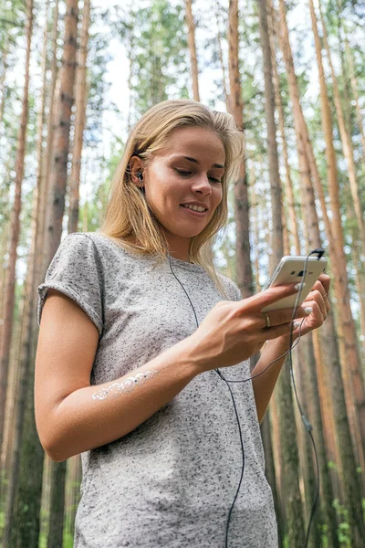Beautiful girl listening to music in forest — Stock Photo, Image