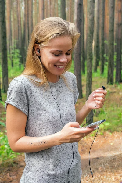 Smiling girl with flash tattoo on arms listening to music — Stock Photo, Image