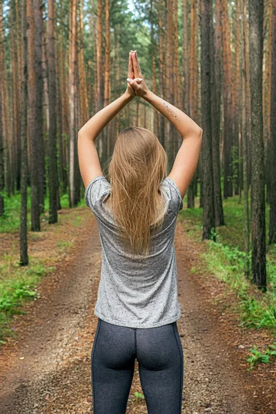 Blonde girl with namaste hands over head in forest — Stock Photo, Image
