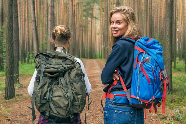 Viajante loira com mochila sorrindo para a câmera perto de sua namorada — Fotografia de Stock