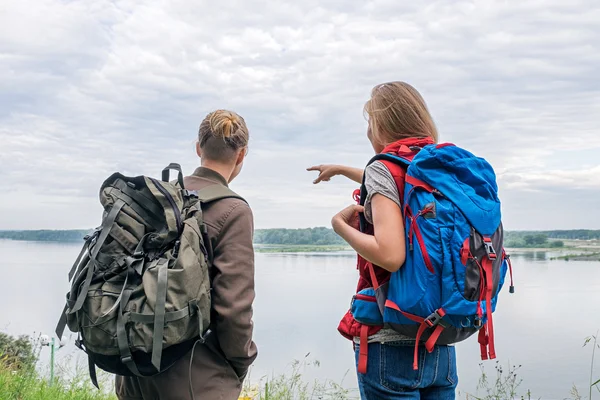 Vista posteriore di giovani zaino in spalla femminili che puntano da qualche parte su un'altra riva del fiume Immagine Stock