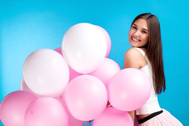 Pretty genç kız hava balonu mavi arka plan üzerinde kamera poz ile yan görünüm