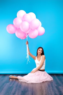 Hava balonları mavi arka plan üzerinde uçan ile şık giysileriyle genç esmer kız portresi