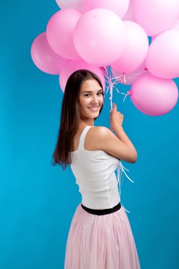 Şirin esmer kız kameraya geriye dönüp baktığımda çok pembe balonlu yan görünüm. Mavi arka plan