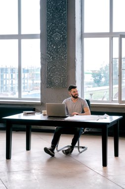 Uzaklara bakan yakışıklı bir mimarın portresi. Arka planda pencereler..