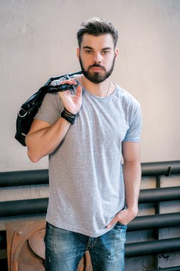 Kameraya poz çanta ile yakışıklı genç bir şık adam portresi