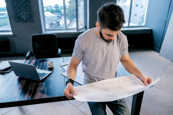 オフィス内のプロジェクトを分析するハンサムな若い建築家 ストックフォト