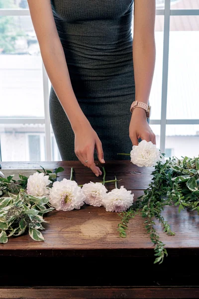 灰色の服をテーブルに新鮮な花とサイプレスの花束を作るで認識できない花屋 ストック画像