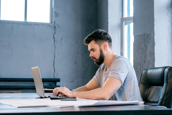 Fiatal Jóképű Üzletember Használ Laptop Asztalnál Rajzokkal Oldalnézete — Stock Fotó